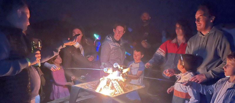 Family holding marshmallows over a fire